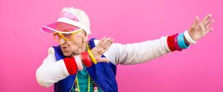 An elderly woman wearing brightly colored, hip clothing doing a funny pose.